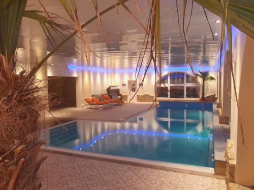 a swimming pool with blue lights in a house at Carea Harz Hotel Allrode in Allrode