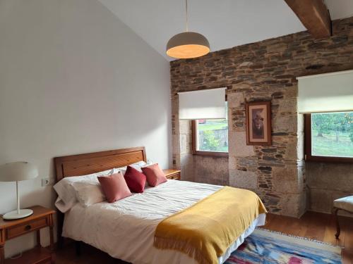 1 dormitorio con cama y pared de ladrillo en Casa da Queira, en Ares