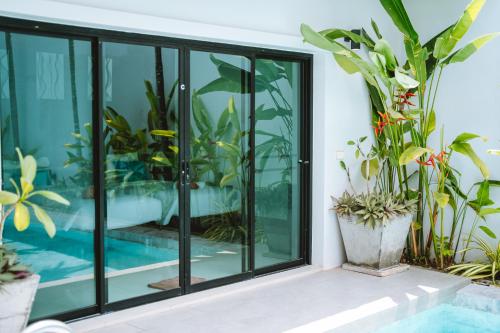 a room with glass doors and potted plants at Layantara Resort, Phuket in Layan Beach