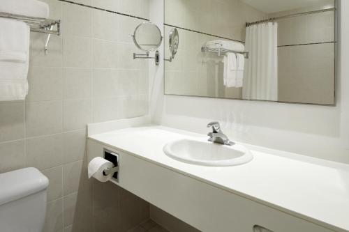 a bathroom with a sink and a mirror and a toilet at Hotel Ruby Foo's in Montréal