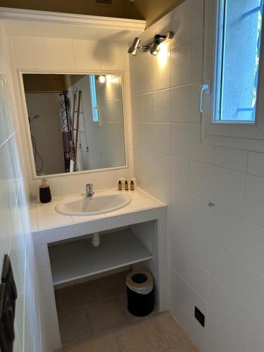 a white bathroom with a sink and a mirror at Bastide Saint-Thomé in Saint-Thomé