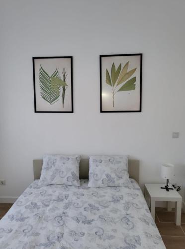 two framed pictures on a white wall above a bed at Bonito piso a 300 m de Metro García Noblejas in Madrid