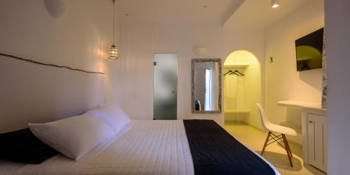 a bedroom with a bed and a chair in it at Fira Vista Hotel in Fira
