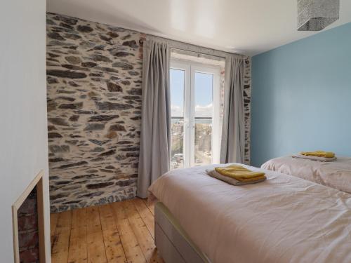 a bedroom with two beds and a stone wall at Windycroft in Barmouth