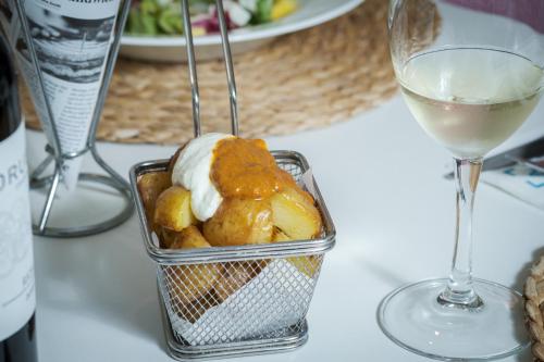 a table with a glass of wine and a container of food at Tres Torres Atiram Hotel in Barcelona