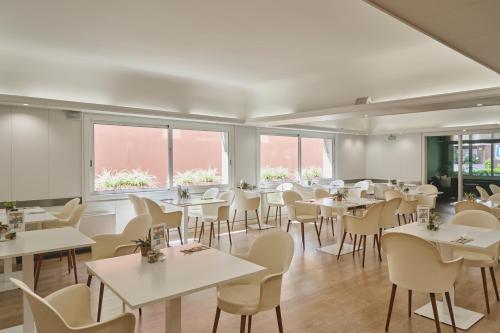 un comedor con mesas, sillas y ventanas en Tres Torres Atiram Hotels, en Barcelona