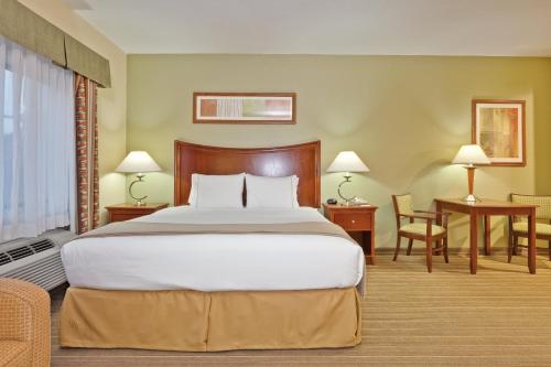 a bedroom with a large bed and a table and chairs at Holiday Inn Express Winfield - Teays Valley, an IHG Hotel in Hurricane