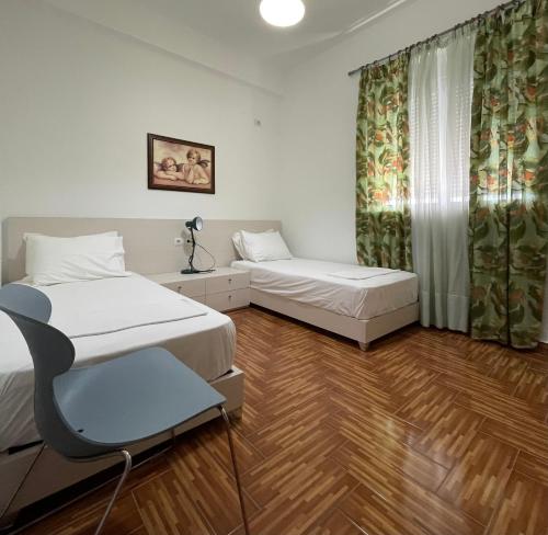 a room with two beds and a chair in it at Port Side Sarande in Sarandë