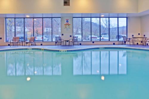 a pool in a hotel room with chairs and tables at Holiday Inn Express Winfield - Teays Valley, an IHG Hotel in Hurricane