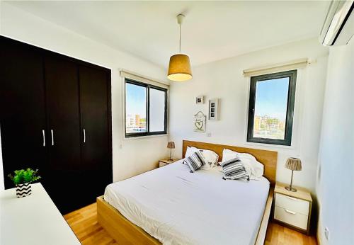 een slaapkamer met een wit bed en 2 ramen bij LARA 303 in Larnaka