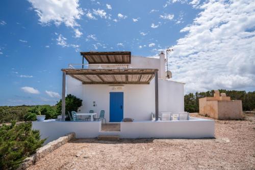 una pequeña casa blanca con una puerta azul en Cas Saliners - Parc Natural en La Savina