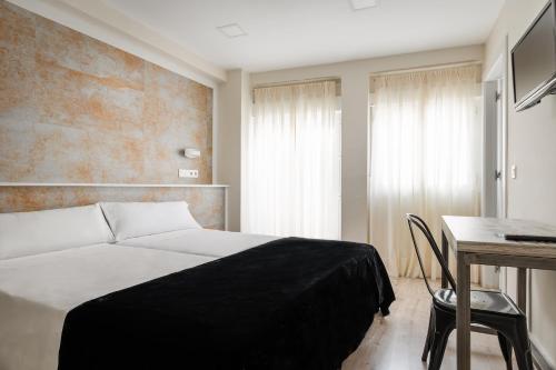 1 dormitorio con cama, mesa y escritorio en YIT Casablanca, en Granada