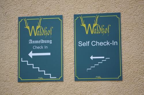 two signs hanging on a wall with a set of stairs at Pension Waldhof am Stubenbergsee in Stubenberg