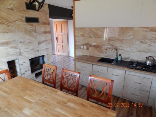 a kitchen with a table and chairs and a fireplace at Caloroczne Domki w Gorach"ALEKSANDER" in Kacwin