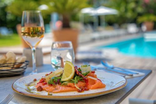 a plate of food on a table with a glass of wine at Mercure Hyères Centre Côte d'Azur in Hyères