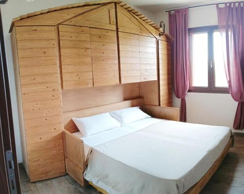una camera con un grande letto con testiera in legno di Villa Salentina Con Ampio Giardino vicina al mare a San Foca