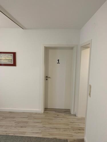 an empty room with a white door and wooden floors at Quartier Wenzelnberg work&stay in Langenfeld