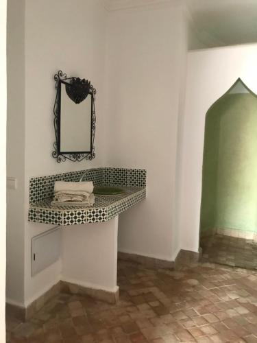 een badkamer met een plank en een spiegel aan de muur bij CHATEAU D'ORIENT in Essaouira
