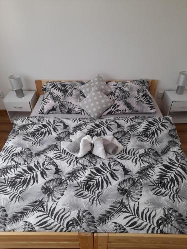 a bed with a black and white comforter with stuffed animals on it at Apartmany Dianka in Veľký Slavkov