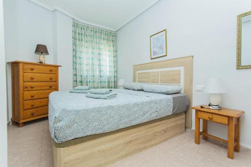 1 dormitorio con cama y tocador de madera en 086 Retro Mayor Holiday - Alicante Holiday, en La Mata