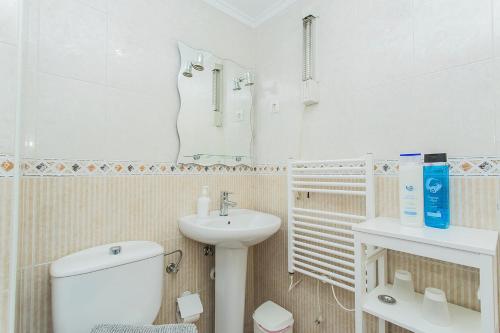 Baño blanco con aseo y lavamanos en 086 Retro Mayor Holiday - Alicante Holiday, en La Mata