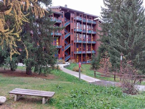 un banc devant un bâtiment rouge dans l'établissement Studio 4 Pers. aux Arcs 1800, Balcon, Proche Pistes, Parking & WiFi - FR-1-411-410, à Arc 1800