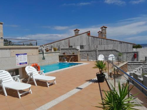 a patio with white chairs and a swimming pool at Remanso do Mar en O Grove in O Grove