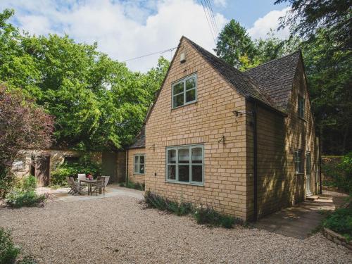 a brick house with a patio and a table at Woodland Cottage in Temple Guiting