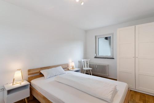 a white bedroom with a large bed and two lamps at Ferienwohnung Emma in Gutach im Breisgau