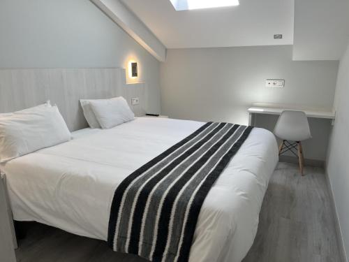 a bedroom with a large white bed with a striped blanket at Santa Filomena in Santiago de Compostela