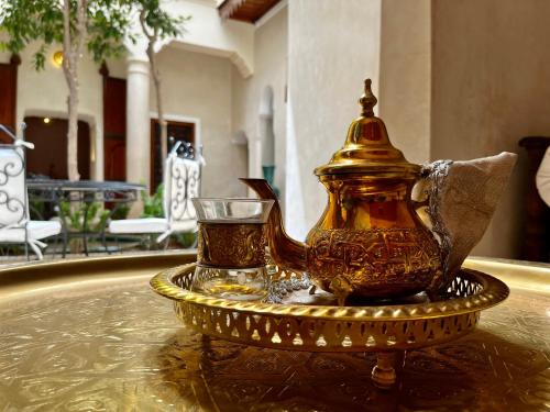 a gold tea pot and a glass on a table at Riad Dar Zaouia in Marrakech