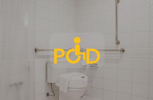 a bathroom with a toilet with a yellow sign on it at Master Porto Alegre Hotel - Av Carlos Gomes, Próximo ao Consulado Americano in Porto Alegre