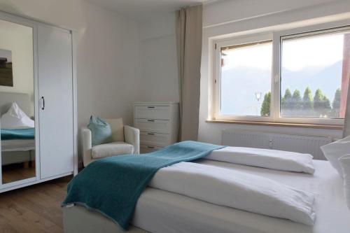 a white bedroom with a bed and a window at Ferienwohnungen BergArt in Iselsberg