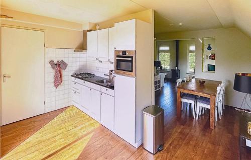 cocina con armarios blancos y mesa de madera con comedor en Nice Home In Sint Nicolaasga With House Sea View, en Sint Nicolaasga