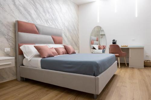 um quarto com uma cama com almofadas cor-de-rosa e um espelho em Sunbay Luxury Rooms em Vieste