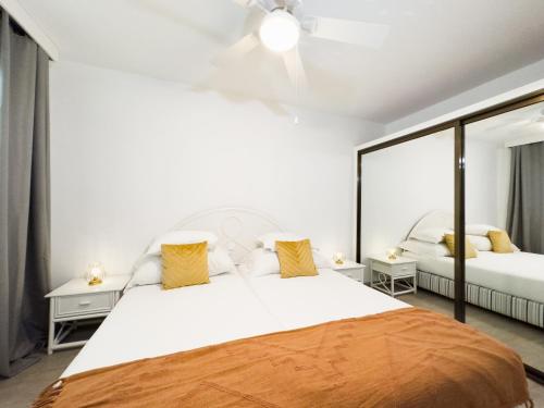 ein Schlafzimmer mit einem großen weißen Bett mit gelben Kissen in der Unterkunft Tranquil Beachside Stay - Atlantic Gardens Beach in Funchal