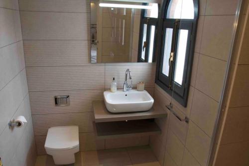 a bathroom with a sink and a toilet and a mirror at Villa with HEATED Pool and Amazing Mountain and Sea Views No Young Groups Allowed in Mojácar