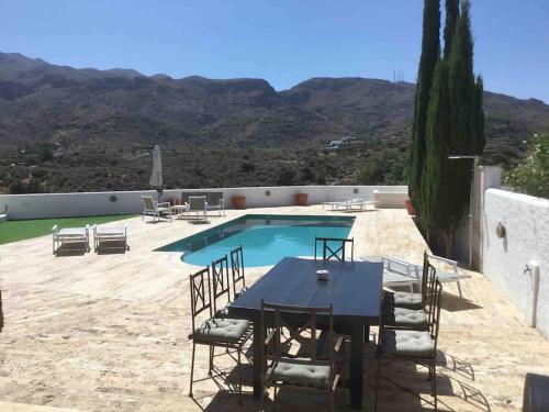 a table and chairs next to a swimming pool at Villa with HEATED Pool and Amazing Mountain and Sea Views No Young Groups Allowed in Mojácar