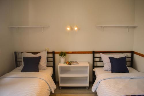 a bedroom with two beds and a nightstand between them at Arcus Premium Hostel in Warsaw