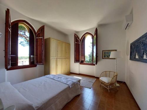 a bedroom with a bed and two windows and a chair at Appartamento La Vista in Cavo