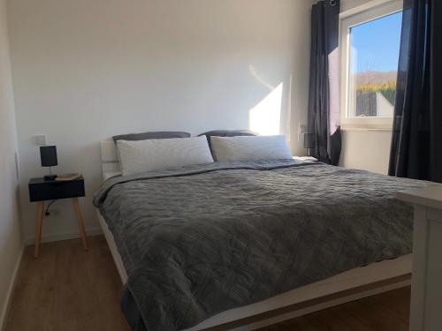 una camera da letto con un grande letto e una finestra di Modernes 2,5 Zimmer Apartment in Eppelborn, privater Eingang, eigener Parkplatz und Terrasse, Deine Ferienwohnung in Eppelborn mitten im Herzen des Saarlandes a Eppelborn