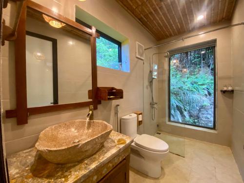 y baño con lavabo de piedra y aseo. en Mường Village Ninh Bình, en Ninh Binh