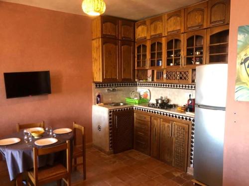 eine Küche mit Holzschränken, einem Tisch und einem Kühlschrank in der Unterkunft Little Paradise House in Agadir