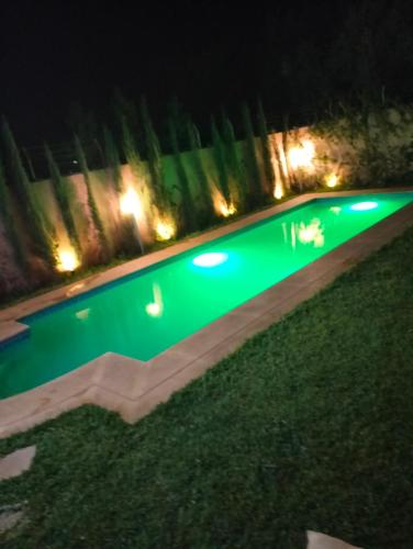 a swimming pool with green illumination at night at Jawharat marrakech in Marrakech