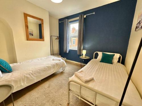 a bedroom with two beds and a blue wall at EasyRest House 3 Grantham - 5 Beds & Free Parking - Easy Location - Access to A1, Town Centre & Shops in Grantham