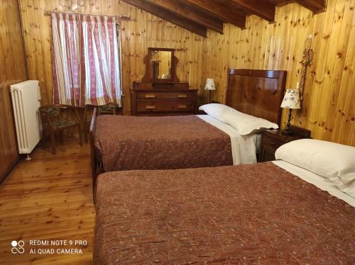 a hotel room with two beds and a mirror at Baita "la Brenva" Pialemont Champorcher - CIR VDA - PONTBOSET 0001 in Pontboset