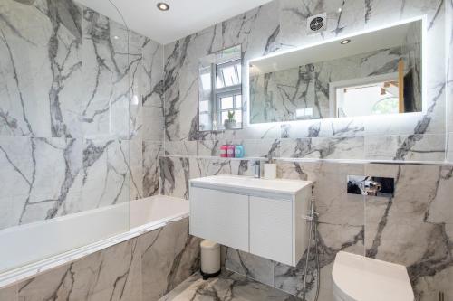 ein Badezimmer mit einer weißen Badewanne und einem Waschbecken in der Unterkunft Home in Saltford with Hot Tub and Sauna. in Saltford
