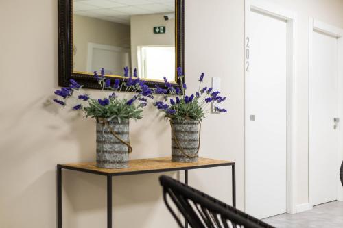 two vases with flowers on a table in front of a mirror at Piccolo Catalunya Hostel in Alghero