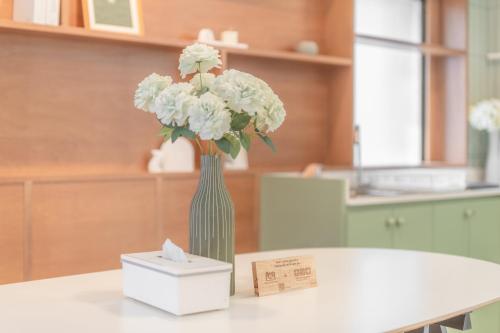 un vase vert avec des fleurs blanches et une boîte blanche dans l'établissement Evergreen apartment by Beginning with, 3BR in heart of Nimman, à Chiang Mai