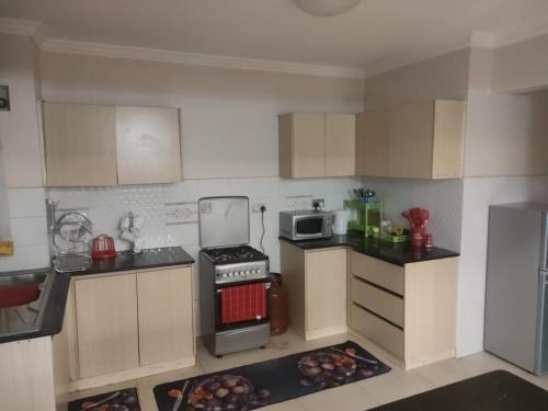 a small kitchen with a stove and a microwave at Zerra Luxury 3 bedroom in Nakuru CBD in Nakuru